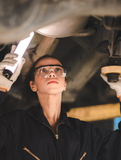 Car mechanic standing under car in garage for inspection