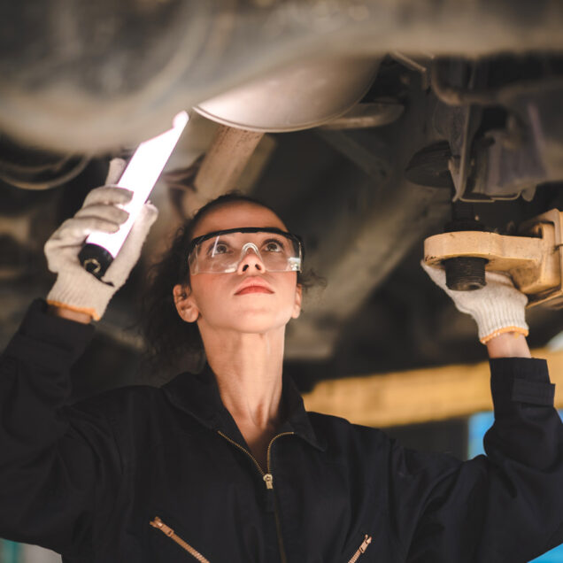 Car mechanic standing under car in garage for inspection