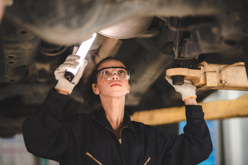 Car mechanic standing under car in garage for inspection