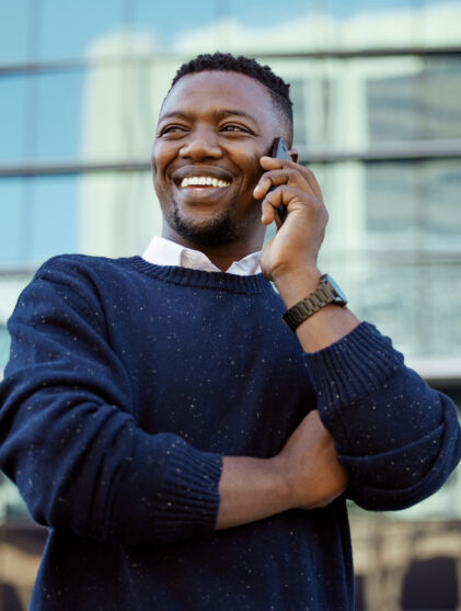 Man smiling and talking to someone on the phone outside of office