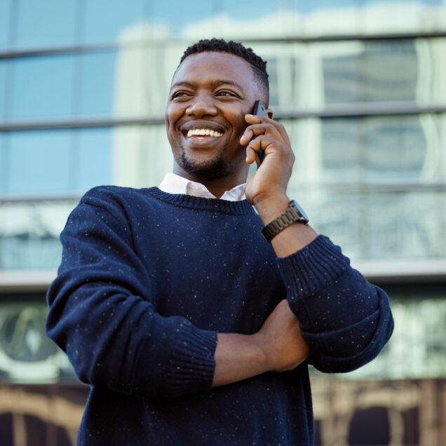 Man smiling and talking to someone on the phone outside of office