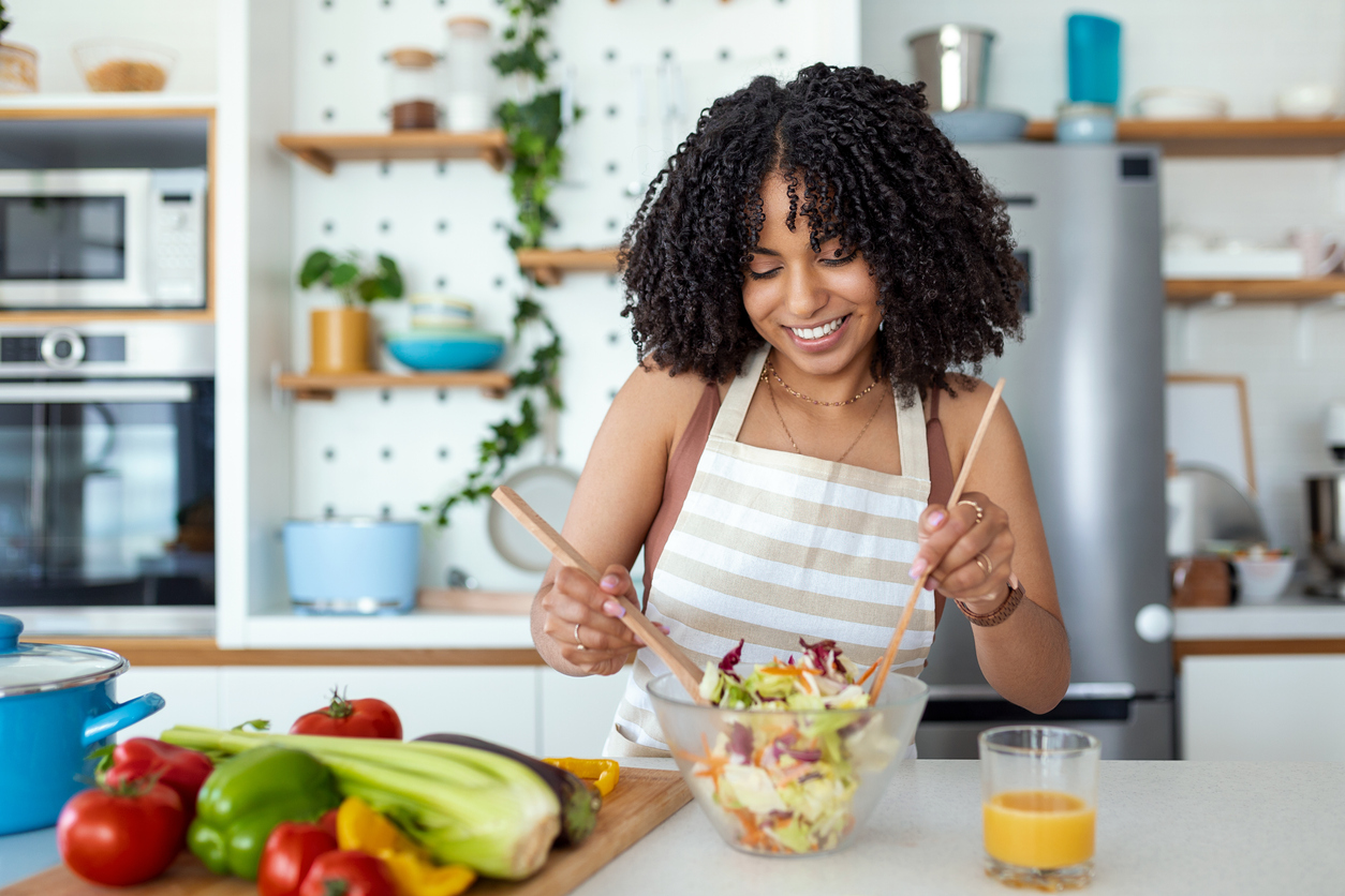 Healthy lifestyle. Good life. Organic food. Vegetables. Close up portrait of happy young woman making a salad in her kitchen.