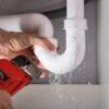 Close-up Of Plumber Fixing White Sink Pipe With Adjustable Wrench