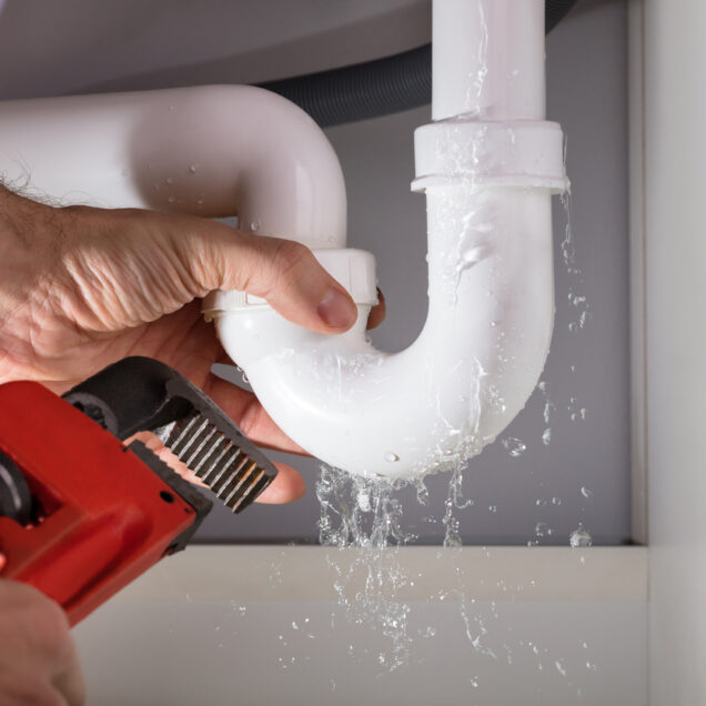 Close-up Of Plumber Fixing White Sink Pipe With Adjustable Wrench