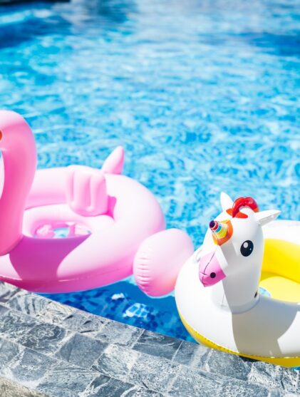 A unicorn pool float and a flamingo pool float sit in a pool