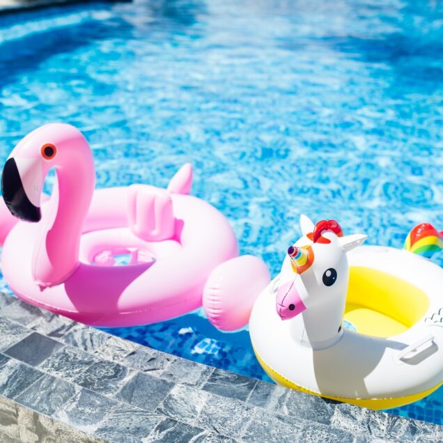 A unicorn pool float and a flamingo pool float sit in a pool