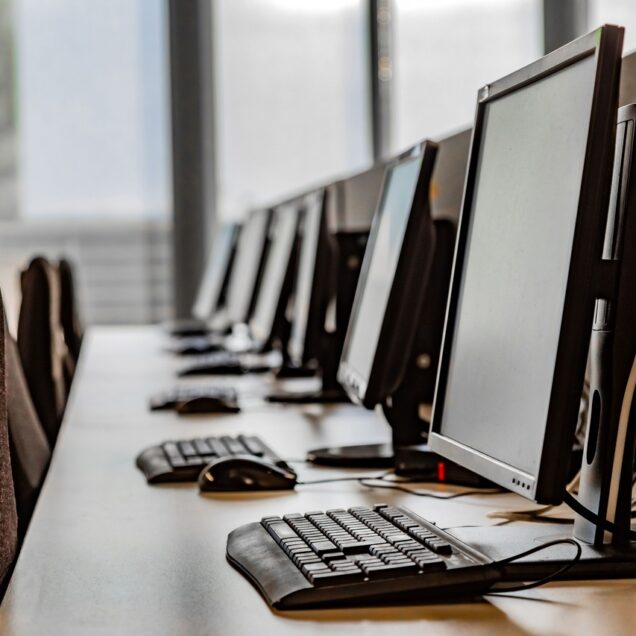 row of computers sit on a desk