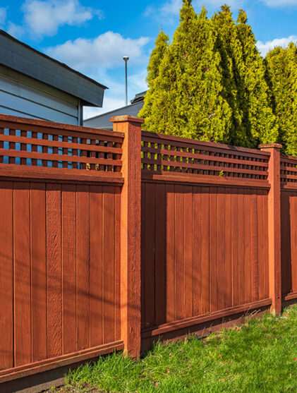 Nice new wooden fence around house. Wooden fence with green lawn. Street photo, nobody, selective focus