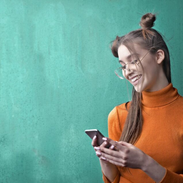 Woman in Orange Turtleneck Sweater Holding Black Smartphone