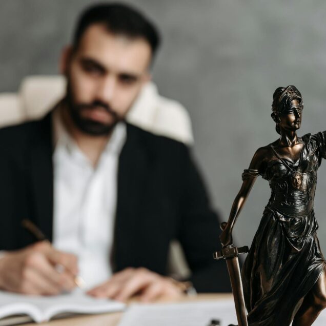 Man in black suit sitting on desk