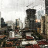 view of the raindrops rolling down the window and the skyscrapers in the surface