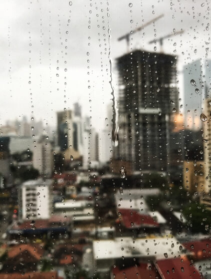 view of the raindrops rolling down the window and the skyscrapers in the surface