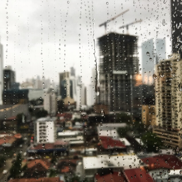 view of the raindrops rolling down the window and the skyscrapers in the surface