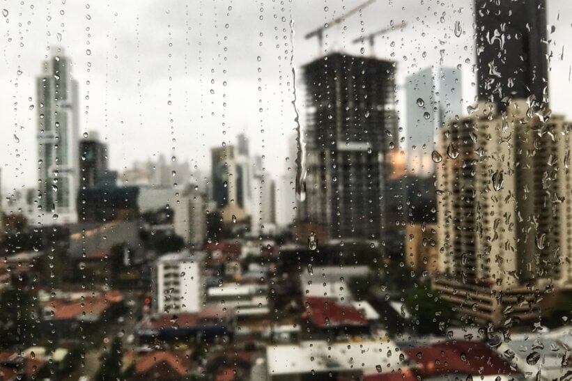 view of the raindrops rolling down the window and the skyscrapers in the surface