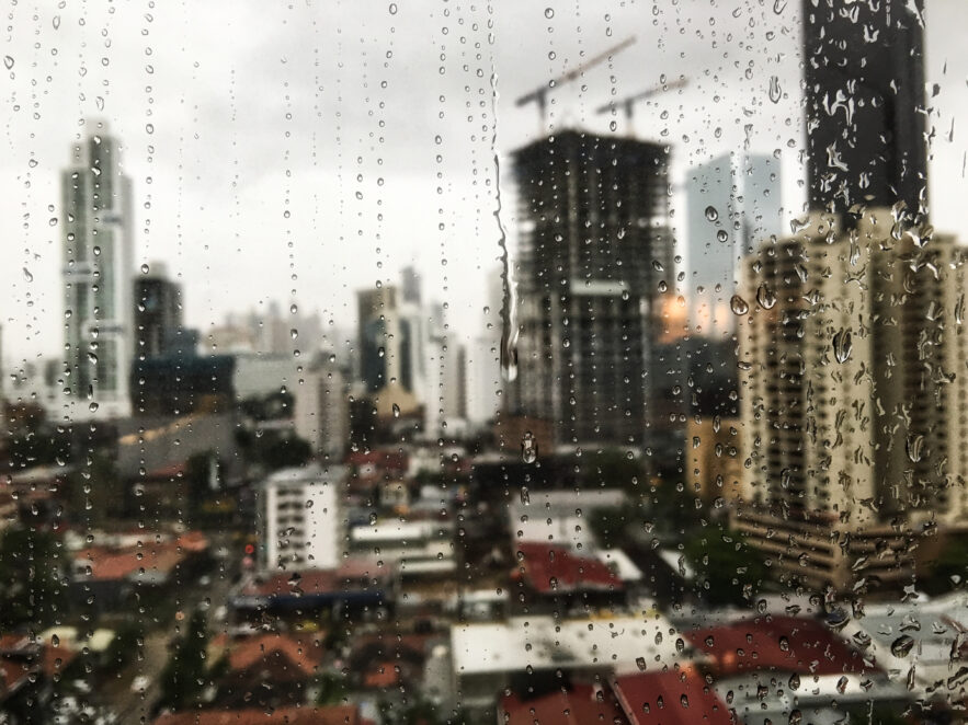 view of the raindrops rolling down the window and the skyscrapers in the surface