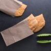 Aerial view of three Jamaican beef patties in brown paper bags with a tong on a black background