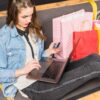 woman next to shopping bags while checking her credit card details and using her laptop