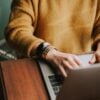 person in yellow brown sweater using a laptop